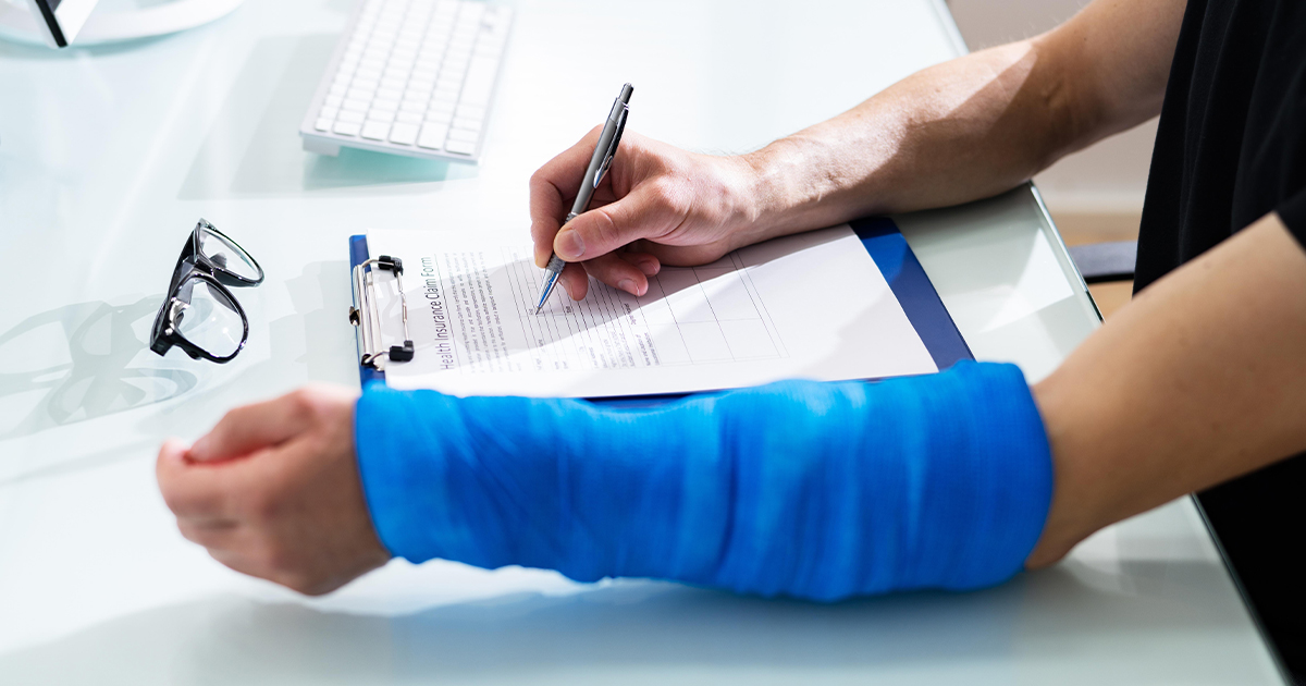 A man with a blue cast is writing on a clipboard, possibly discussing Personal Injury Protection (PIP) in Texas.