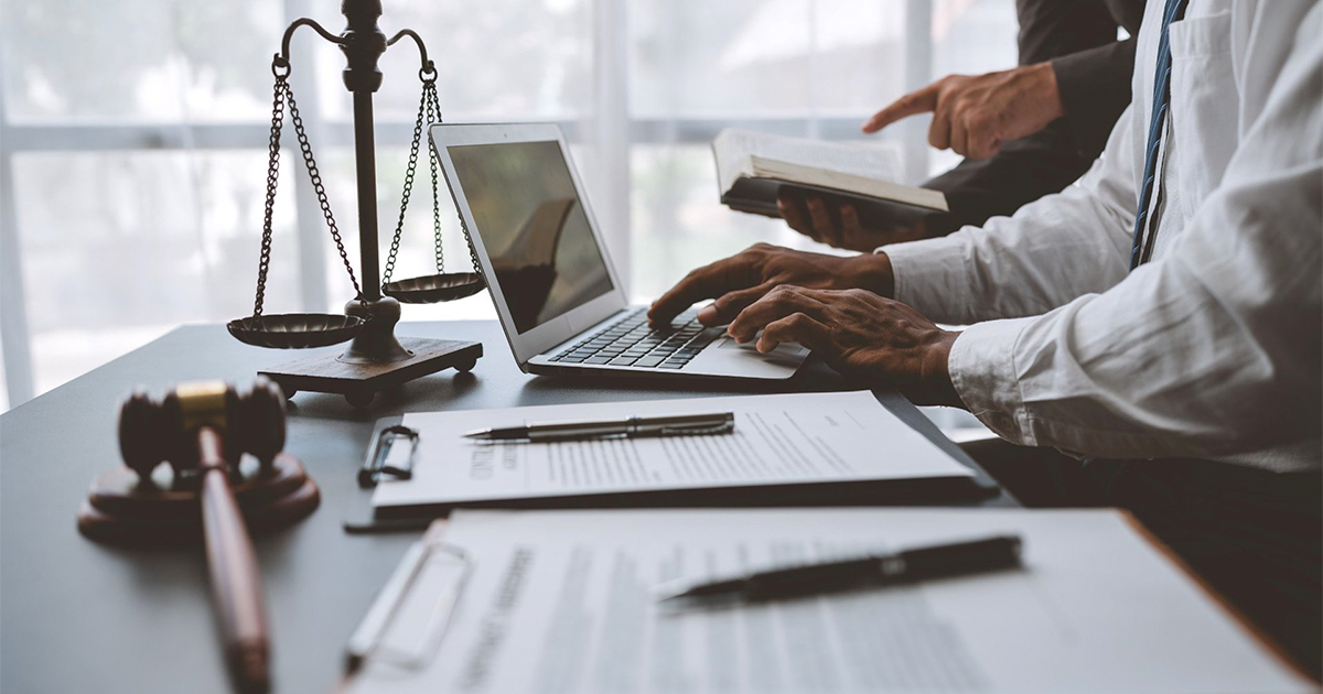 A man in a suit sits at a desk with a laptop and a scale, contemplating personal injury settlements in Texas.