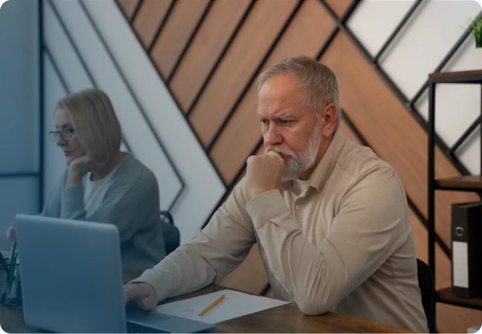 Elderly man looking concerned while working on a laptop, symbolizing challenges of age discrimination in the workplace.