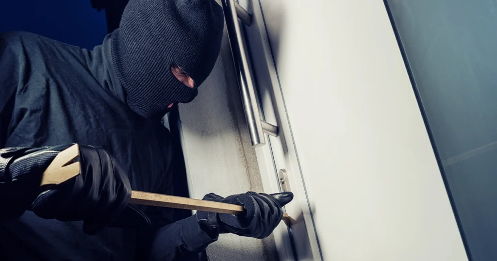 Person in black clothing committing a property crime at night